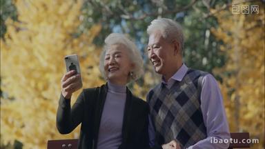 <strong>幸福</strong>的老年夫妇坐在户外用手机拍照